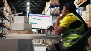 African american overworked woman struggling to stay awake, dealing with burnout after a long shift of processing orders in industrial warehouse space. Exhausted staff member. Camera A. video