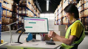 Distribution hub staff printing and applying awb labels on packages, wearing hi vis vest in a storehouse. Using barcode airway bill and shipping labels for order fulfillment and tracking. Camera A. video