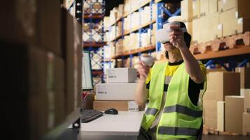 Asian man uses virtual reality headset and tracking software near industrial storage racks, processing orders. VR device to update tracking info on parcels, artificial intelligence. Camera A. video