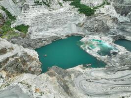 Open pit mine industry. Limestone quarry with truck. Heavy machinery in mining industry and construction material supply. Landscape of resource extraction in industrial site. Turquoise water lake. photo
