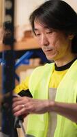 Vertical Tired overworked person in hi vis vest scanning shipping labels, being sleepy and bored with his tasks in the warehouse. Managing order fulfillment with a scanner and tracking software. Camera B. video
