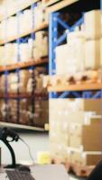 Vertical Asian warehouse worker scanning shipping labels and barcodes on packages, using scanner to verify shipment details on parcels before distribution. Man works near racks with hi vis vest. Camera A. video