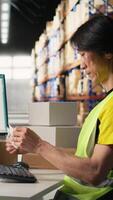 Vertical Distribution hub staff printing and applying awb labels on packages, wearing hi vis vest in a storehouse. Using barcode airway bill and shipping labels for order fulfillment and tracking. Camera A. video