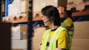 Call center male worker answer help line calls in a logistics warehouse, updating clients on orders and resolving cargo mix ups. Managing shipping software and airway bills. Camera B. video