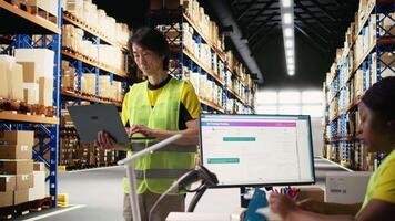 Asian industrial employee organizes goods and processes online shopping orders, coordinating delivery. Man handles packaging and manages inventory, working efficiently for clients. Camera A. video