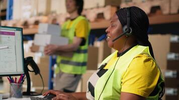 Black female customer support clerk speaks with clients about shipment details, helping with wrong address mix up on the help line. Woman resolves order, confirm airway bill numbers. Camera B. video