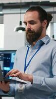 Vertical System administrator in office developing software applications, integrating AI driven automation in operations. IT expert using laptop, debugging applications to resolve issues, camera A video