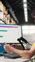 Vertical Asian warehouse worker uses AI virtual assistant to help manage inventory, scanning barcodes to update shipping labels and deliver accurate order processing. Online shopping activity. Camera A. video