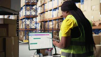 Warehouse employee using package tracking software on computer monitor, managing express delivery and using awb tracking info to update real time parcel status. Distribution hub. Camera A. video