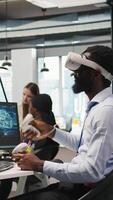 Vertical Programmer wearing VR headset at office desk developing programs using AI automation. Startup worker using virtual reality technology, debugging applications with artificial intelligence, camera A video
