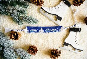 Woven friendship bracelet with alpha pattern Snowy night with houses and Let it snow. Handmade of thread, on background with spruce cones, photo