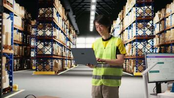 Warehouse employee in hi vis vest preparing packages for local delivery, processing custom orders and handling merchandise within large business operation focused on e-commerce. Camera A. video