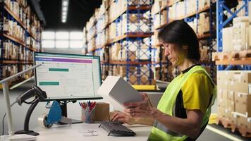 Worker verifying cardboard boxes and awb tags for parcel tracking, handling order processing before distribution. Man in hi vis vest working in e-commerce warehouse with industrial racks. Camera A. video