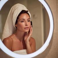 A woman in a towel is looking at her face in a mirror photo