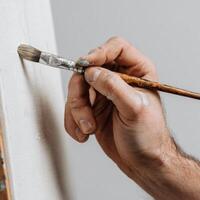 A person holding a brush and painting a canvas photo