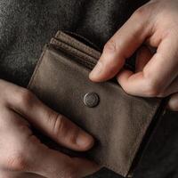 A person holding a brown wallet with a button photo