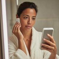 A woman in a robe is looking at her phone photo