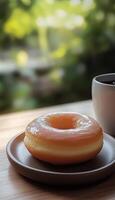 Glazed donut on ceramic plate and tea drink for simple breakfast, story vertical nature background photo