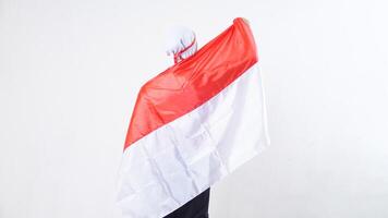 Close up of rear view of muslim girl celebrate Indonesia independence day in red and white outfit holding and wrapping herself with Indonesian flag isolated on white background photo
