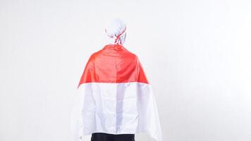 Close up of rear view of muslim girl celebrate Indonesia independence day in red and white outfit holding Indonesian flag behind her back isolated on white background photo
