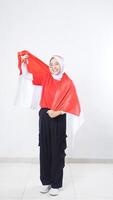 Happy Asian girl celebrate Indonesia independence day in red and white outfit showing patriotic pose with Indonesian flag draped around her back like a cape isolated on white background photo