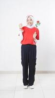Happy Asian girl celebrate Indonesia independence day in red and white outfit showing winning gesture with raising clenched fist while holding a rose isolated on white background photo