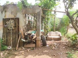 The ruins of an abandoned house. An empty house with moss-covered walls, a collapsed roof, and neatly stacked wooden debris. Abandoned area with copy space. photo