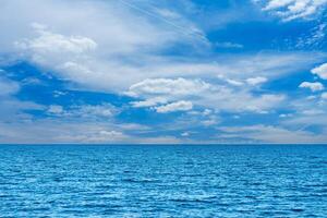 Enjoy the calm of the ocean beneath a bright blue sky with fluffy clouds. This peaceful seascape embodies tranquility and natural beauty, ideal for relaxation and inspiration. photo