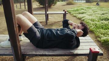 Man Trains on a Wooden Bench in the Outdoor Park Sport video