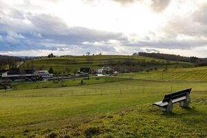 Bench on a hill near a village in sunlight photo
