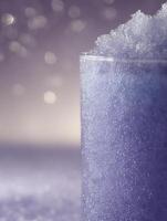 Close up of a glass filled with a purple bubbly beverage, shimmering bokeh background. photo