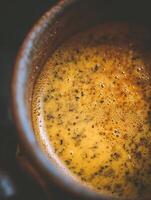 Close up of Frothy Turmeric Tea in a Rustic Mug. photo