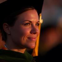 Portrait of a Happy Graduate at Sunset. A close up image of a young woman in her graduation cap and gown, bathed in the warm light of the setting sun. photo