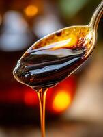 Close up of Golden Syrup Dripping from a Spoon. A Detailed Image Showing the Texture and Flow of Sweet Molasses. photo