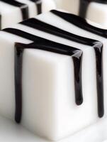 Close up of white dessert cubes with dark chocolate syrup drizzled on top. photo