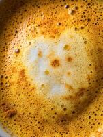 Close up of Golden Turmeric Latte Foam Texture. A detailed image showcasing the rich, bubbly texture of a turmeric latte. photo