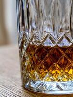 Close up of Crystal Glass with Amber Liquid. A detailed image showcasing the intricate cut glass and rich color of the beverage within. photo