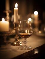 A glass of amber liquid sits on a table illuminated by candlelight, creating a warm and inviting atmosphere. photo