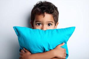 Shy Mexican boy holding pillow while standing against white background photo