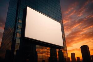 Prominent blank billboard on contemporary building facade at dramatic sunset photo