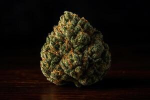 High detail macro shot of a single cannabis bud on a dark wooden surface photo