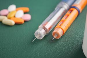 Medications and insulin on a green surface photo