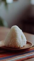 Close Up of a Triangular Onigiri Rice Ball on a Wooden Plate. photo