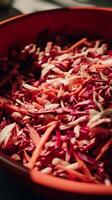 Close up of a vibrant red cabbage and carrot salad in a red bowl. photo