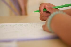 Child practicing writing with a green marker at home photo