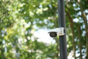 Security camera mounted on pole in a lush green area photo