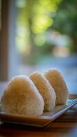 Close up of three onigiri rice balls on a plate, soft focus background. photo
