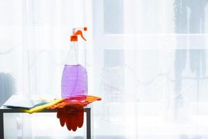 A bottle of cleaning solution and gloves on a table photo
