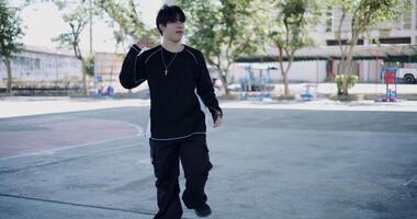 Handheld wide view shot, A stylish Asian man is practicing freestyle dancing alone in a park dome. Enjoy the rhythm and creativity. Solo dance. video