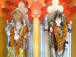 Lord Ganesha and Lord Shiva statues decorated with flower garlands in hindu temple in Rishikesh, India. photo
